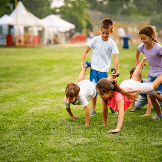 A group of children doing push ups on a grassy field.