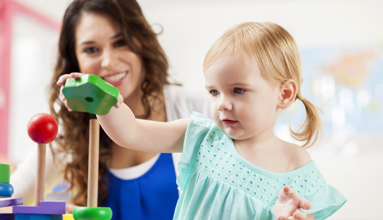 A young girl is playing with a toy in a playroom.