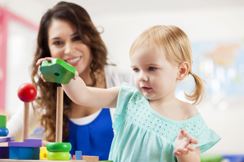 A young girl is playing with a toy in a playroom.