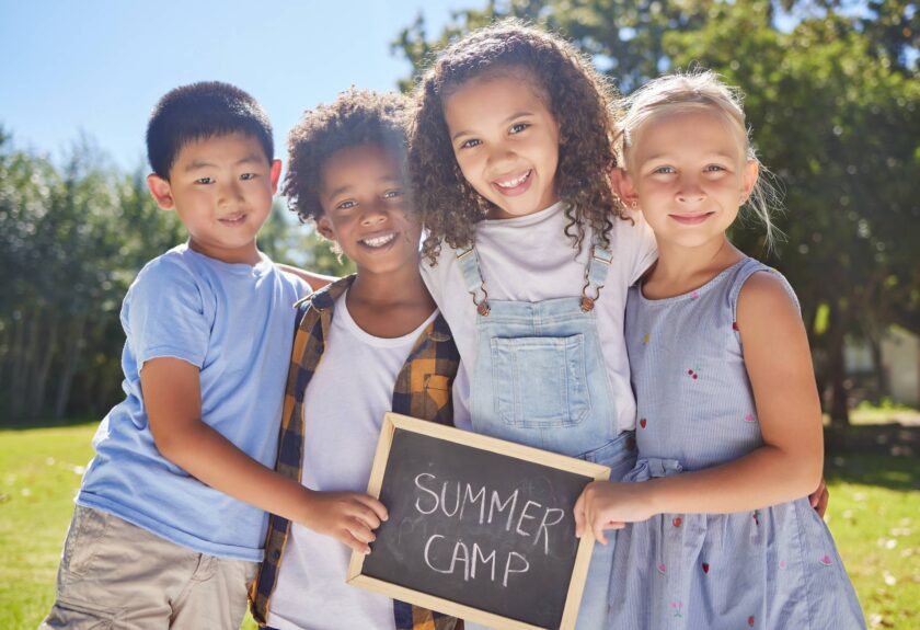 Kids posing with a summer camp sign.