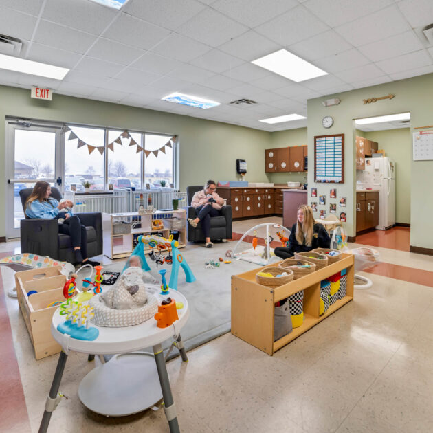 A nursery with two women in recliners giving bottles to babies.