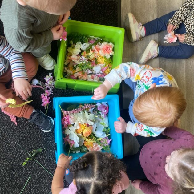 A group of children playing with buckets of flowers.