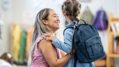 Child with a backpack saying hello to a woman.